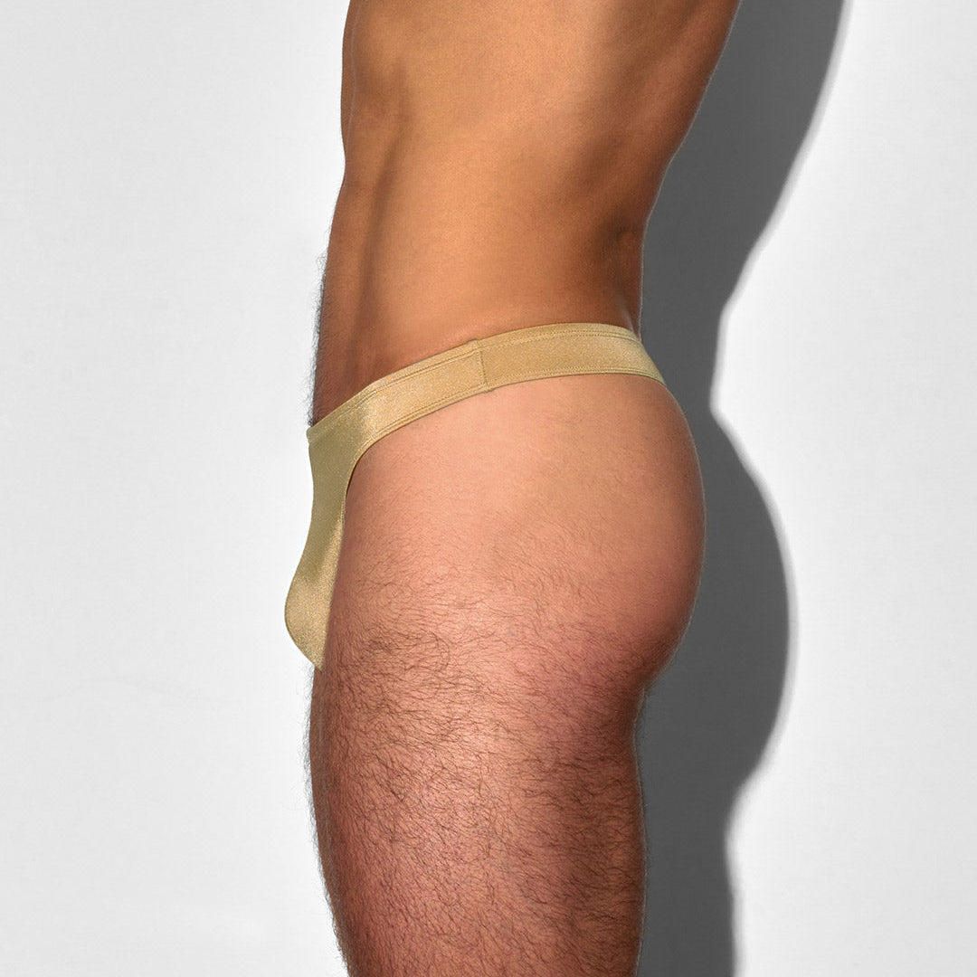 Champaign-nude colored swim thong worn by a person on a white background