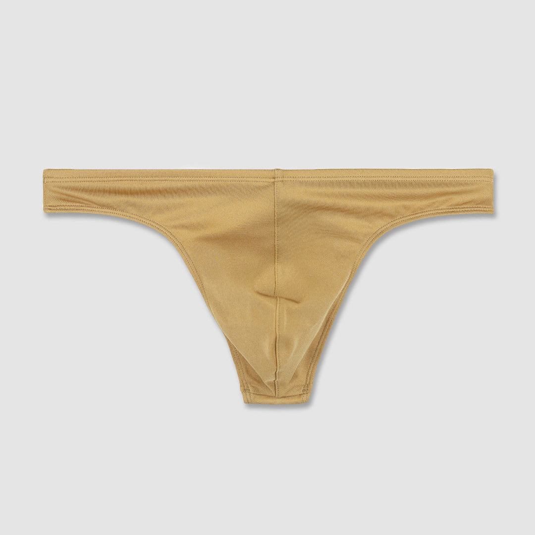A pair of low-rise, thong-style bikini swim bottoms in a solid champaign-nude color, displayed flat against a light gray background.