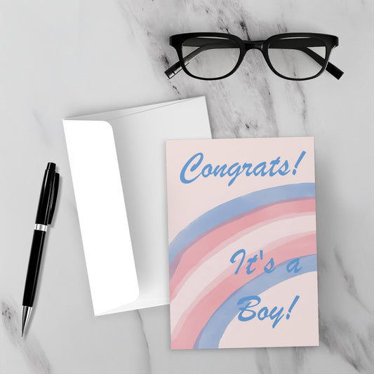 Greeting card with 'Congrats! It's a Boy!' text on a marble surface with glasses and pen.
