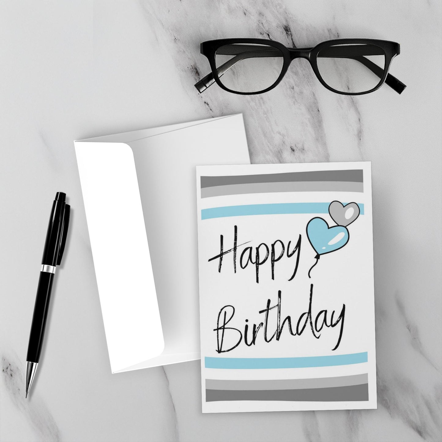 demiboy Birthday card with blue heart and gray stripes on a marble surface with glasses and pen.
