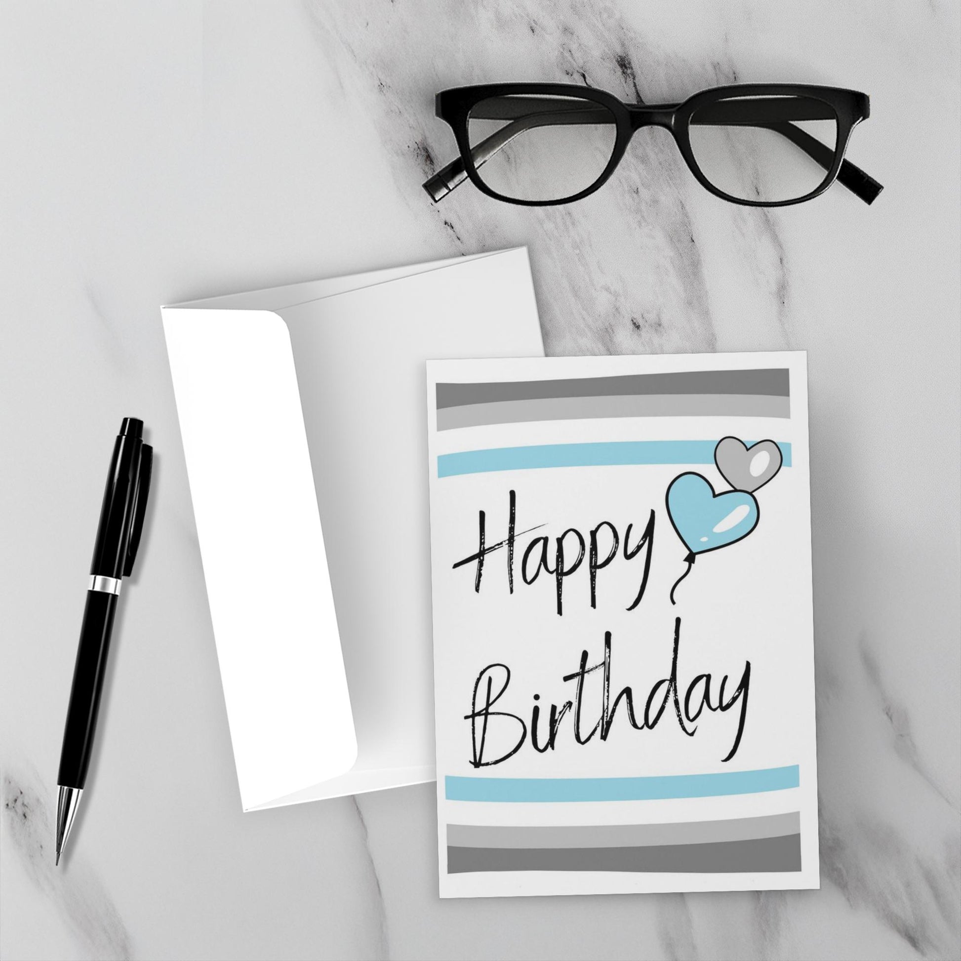 demiboy Birthday card with blue heart and gray stripes on a marble surface with glasses and pen.