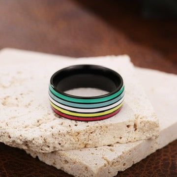 Black ring with colorful disability pride stripes on a stone surface