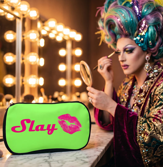 person applying make up in a mirror with a green cosmetic bag beside them with the text 'slay' and lipstick print in hot pink