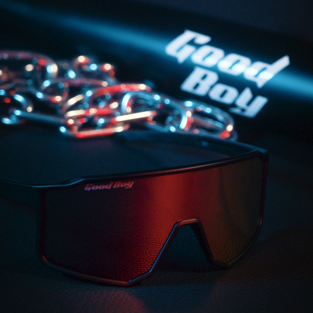 black sunglasses with 'Good Boy' branding on a black leather background