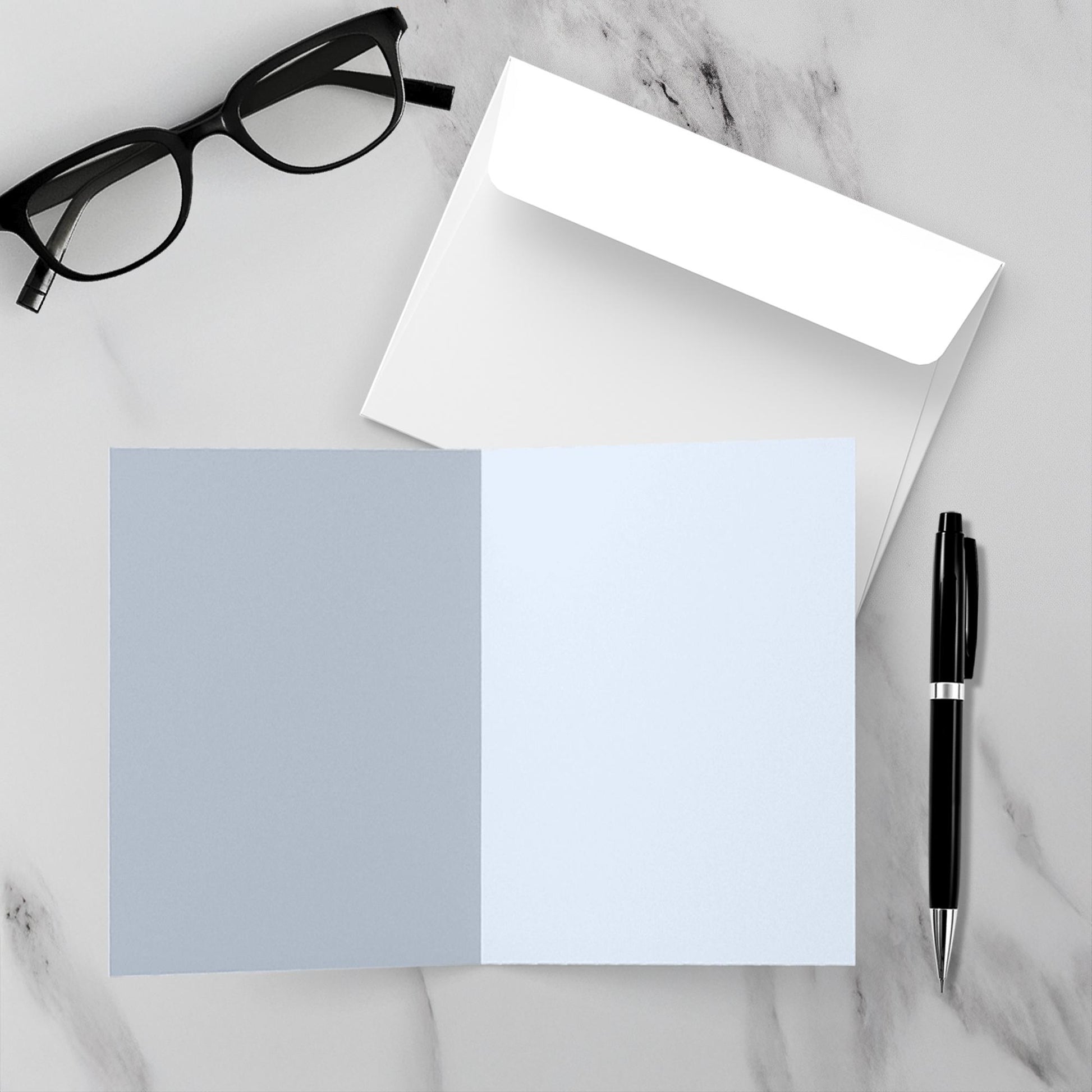 inside greeting card is blank on a marble surface with a pen, glasses, and an envelope