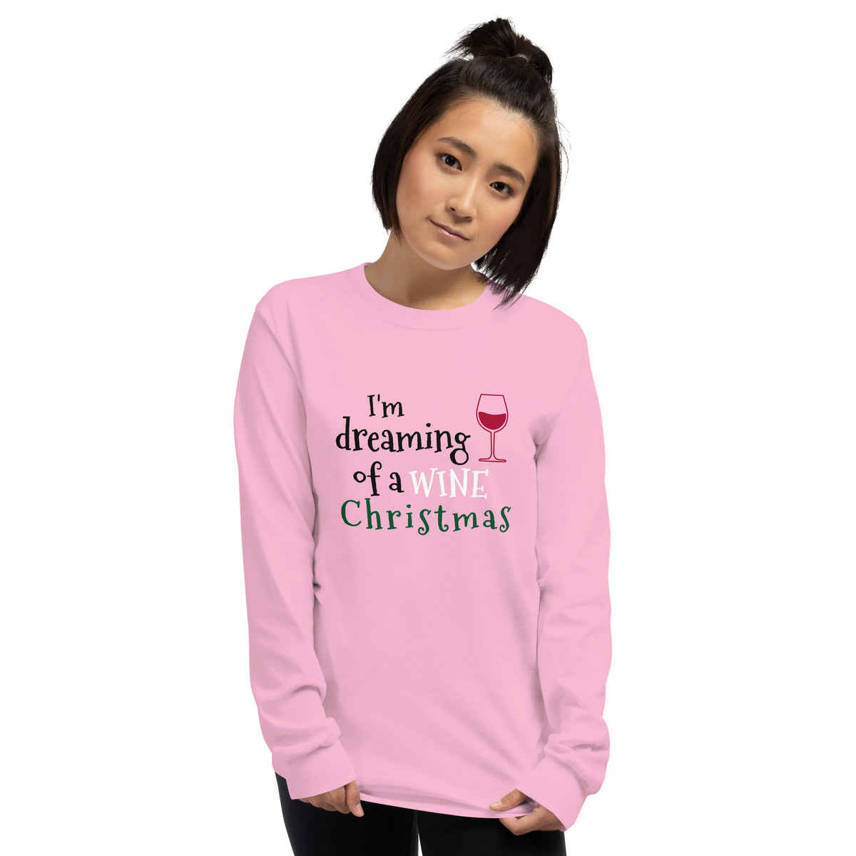 person wearing a pink long sleeve tee shirt with a red wine glass and text that reads 'I'm dreaming of a wine Christmas' in black, white, and green letters