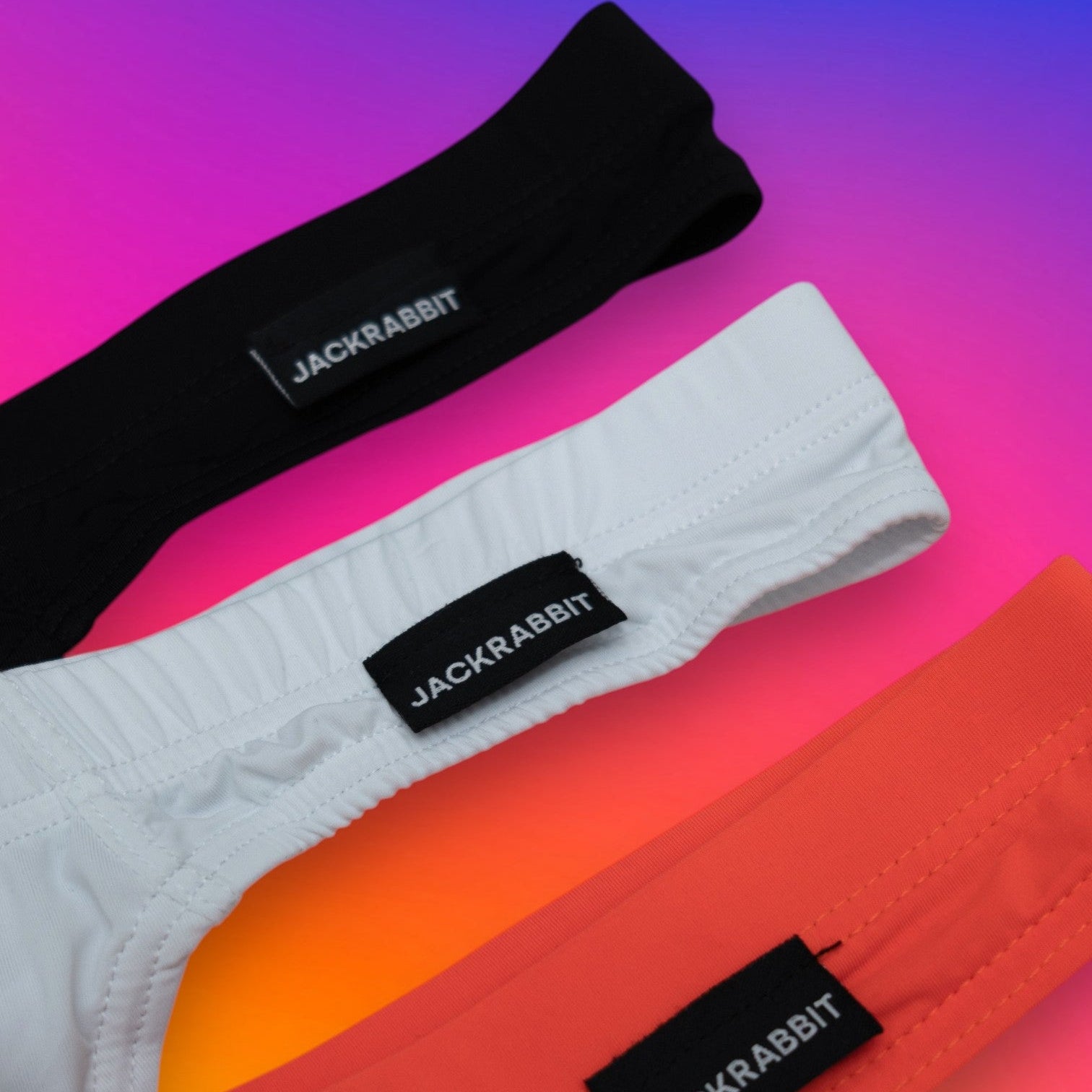 Three pairs of socks in black, white, and orange with 'Jackrabbit' branding on a gradient background.