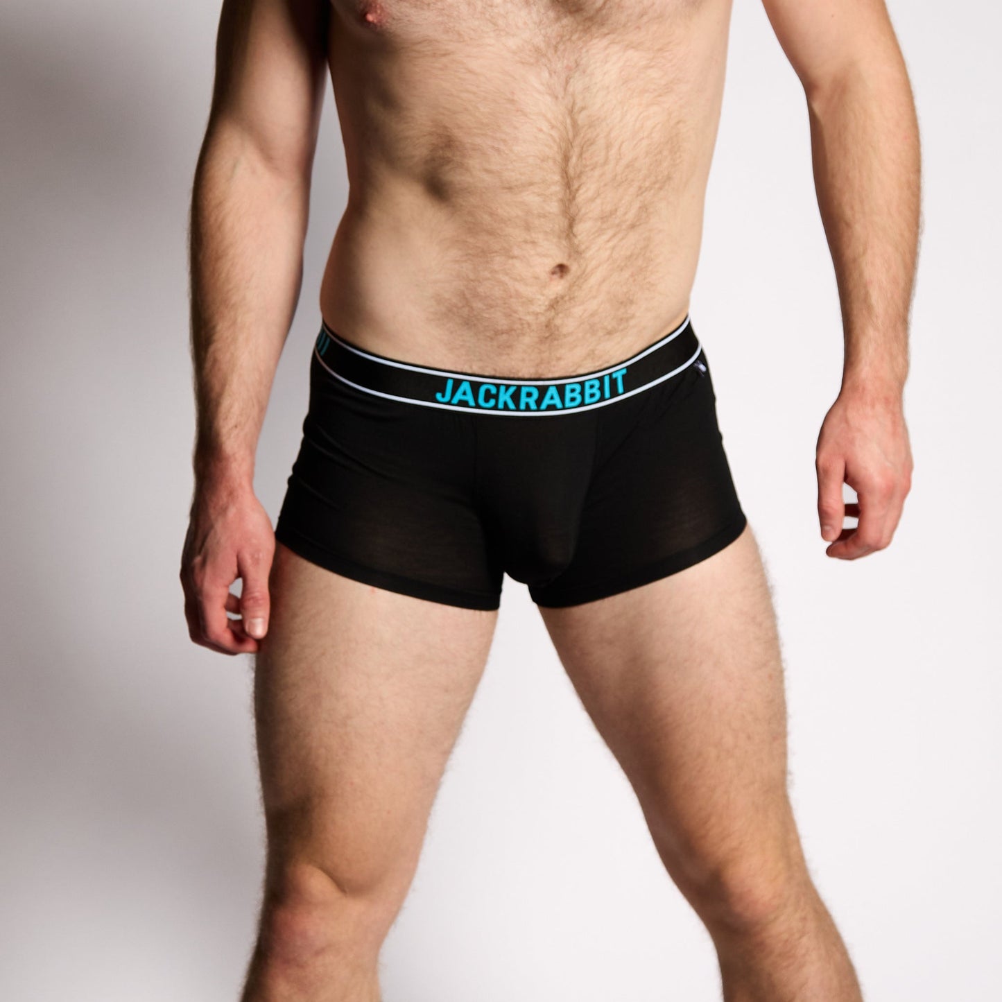 Man wearing black underwear with a visible jackrabbit brand logo on a plain background