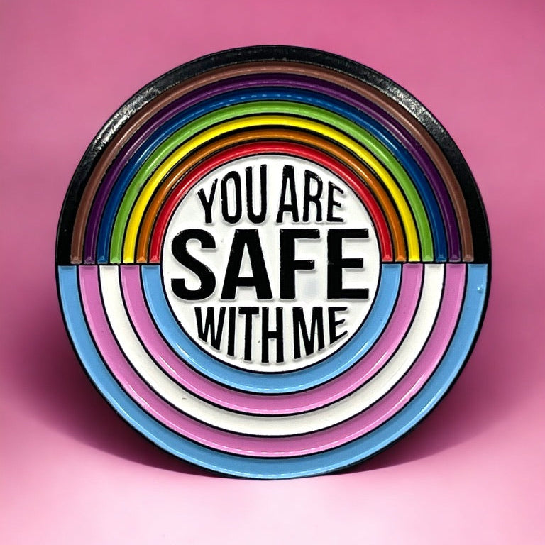 Circular lapel pin with rainbow design and 'You Are Safe With Me' text on a pink background