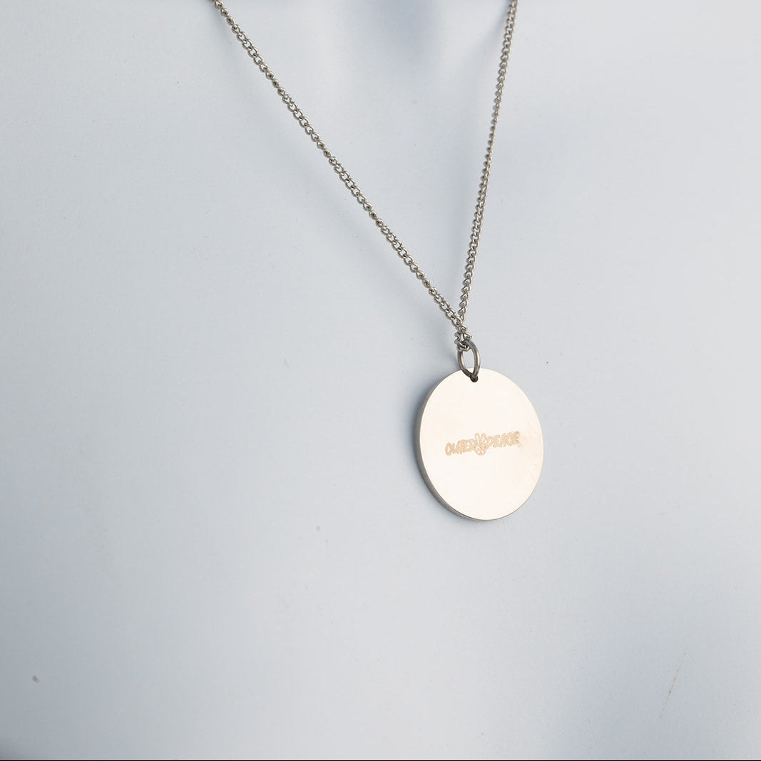 Back of necklace with a round pendant on a light gray background