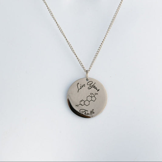 Silver necklace with a round pendant that says 'Live your Truth' with a chemical symbol on a light gray background