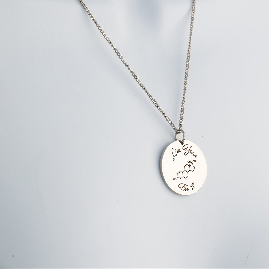 Silver necklace with a round pendant  that says 'live your truth' with a chemical symbol on a light gray background