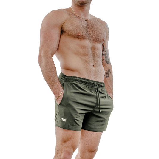Man wearing sage green athletic shorts with a visible 'THK' brand logo on a white background