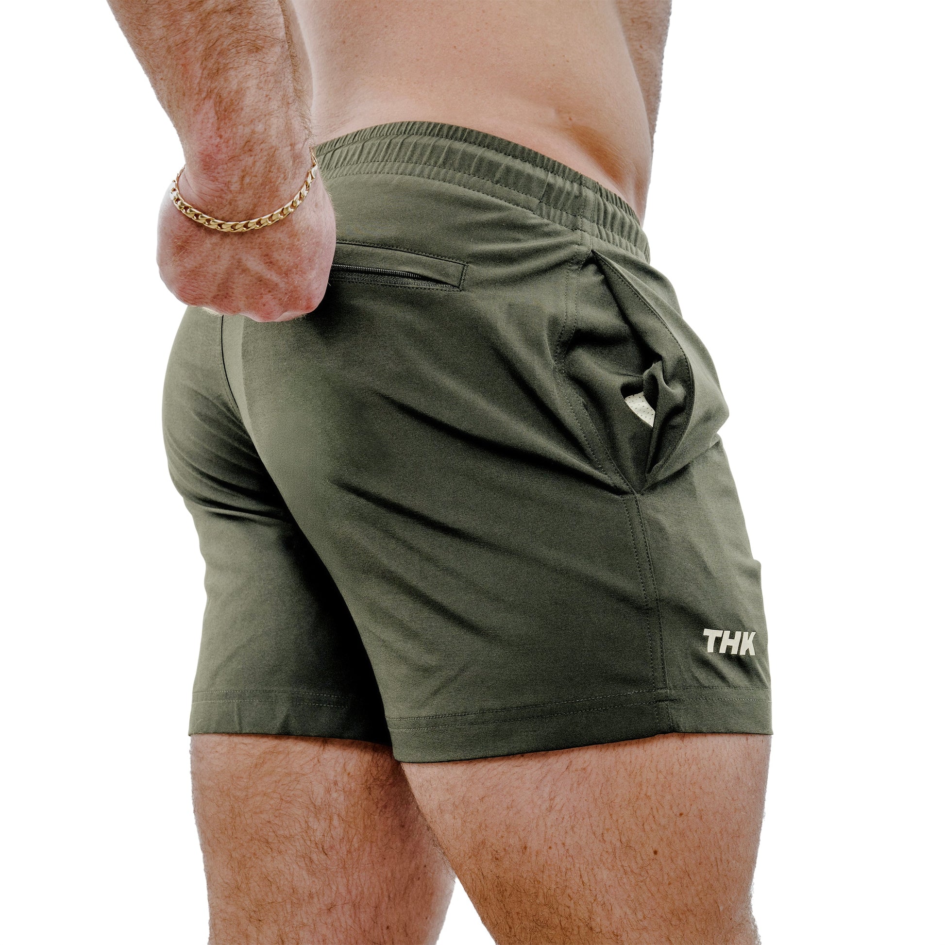 Man wearing sage green gym shorts with a brand logo on a white background