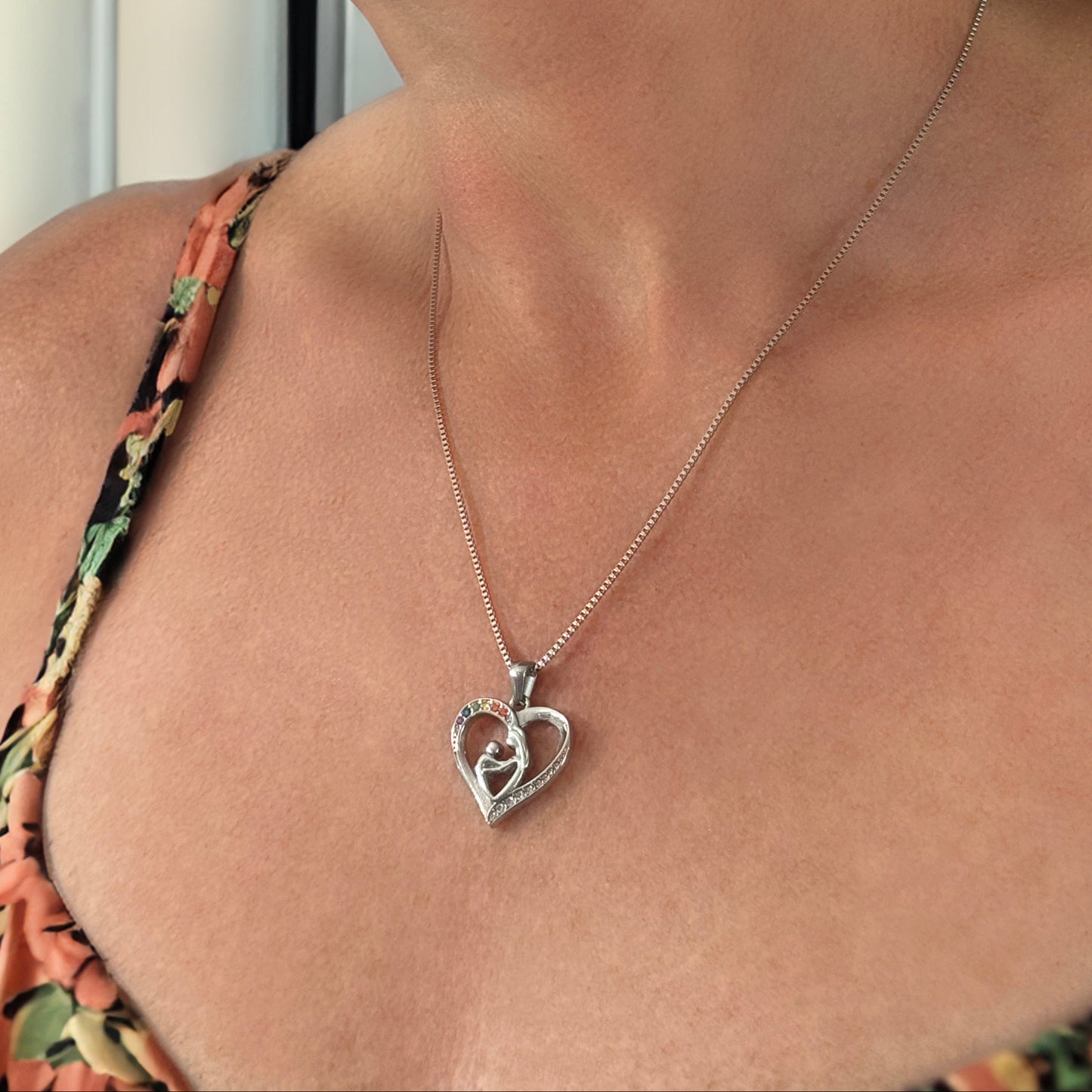 Woman wearing a floral top and a silver heart-shaped necklace.