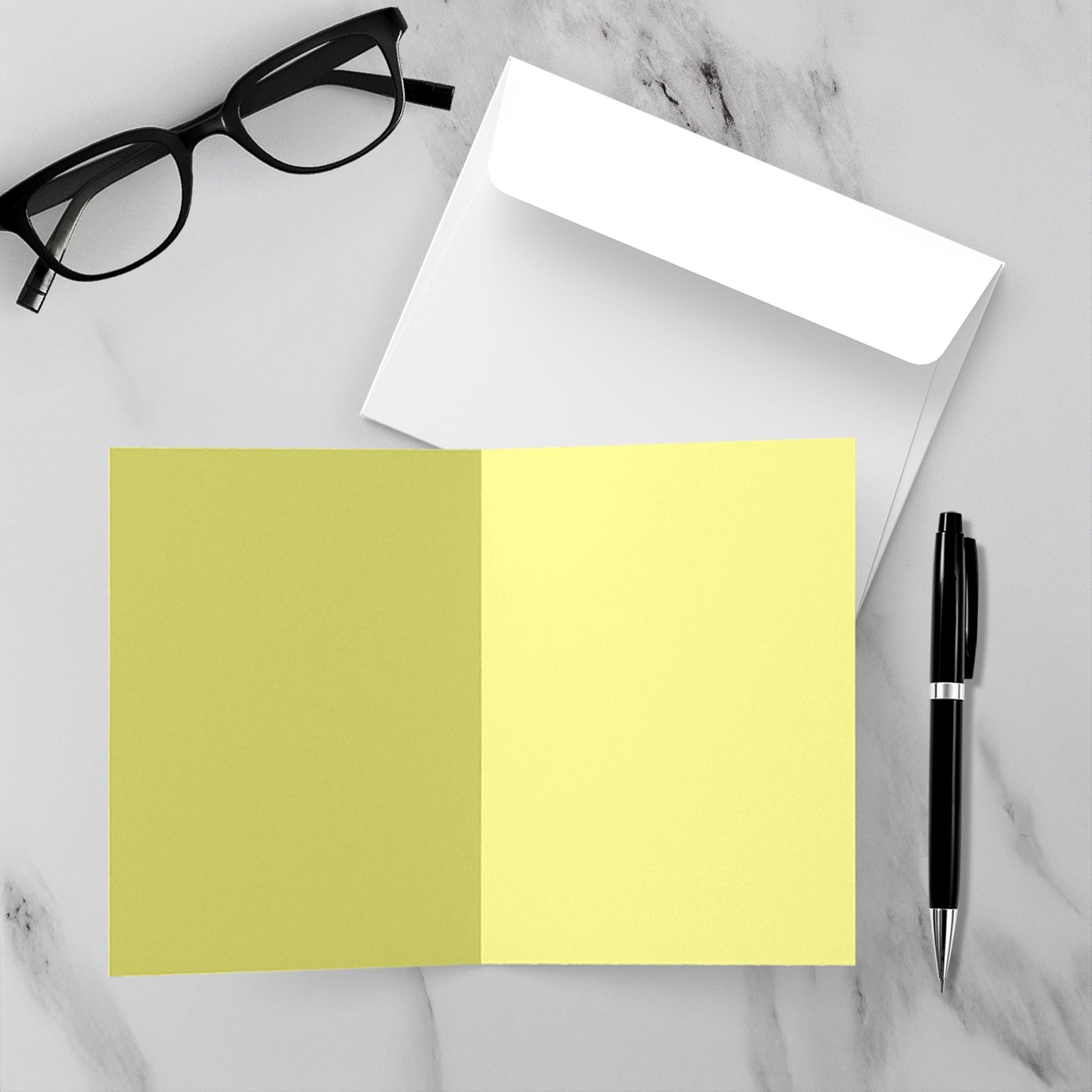 blank yellow inside of card, black pen, and glasses on a marble surface