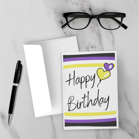 Nonbinary birthday card with heart and stripes on a marble surface with glasses and pen.