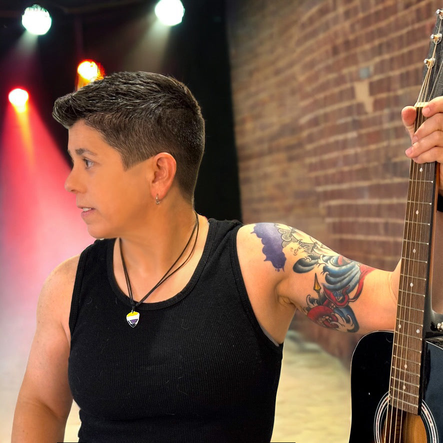 Person holding a guitar on a stage with brick wall background