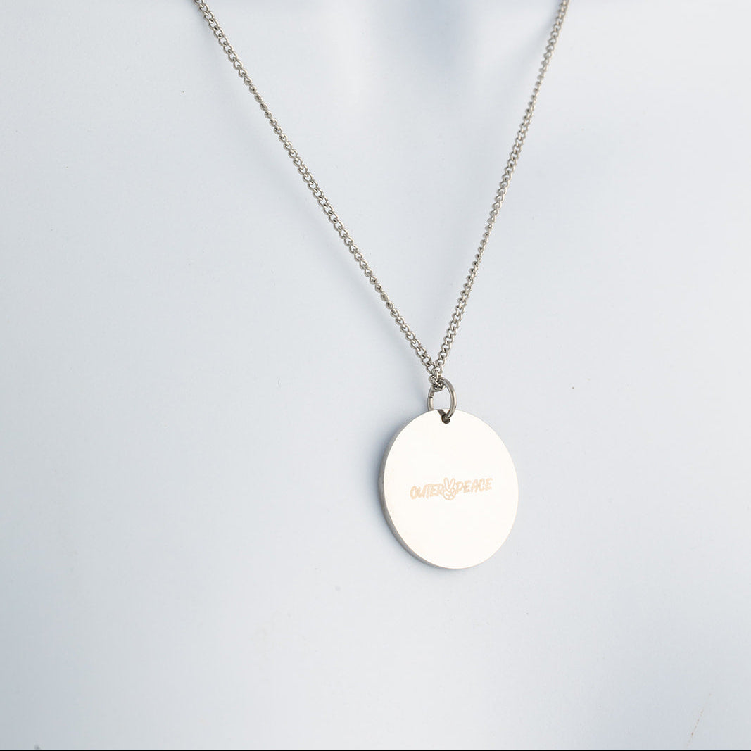 Silver necklace with a round pendant on a light gray background