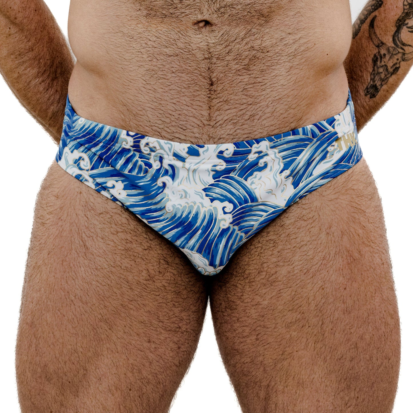 Blue and white wave patterned swim briefs worn by a person on a white background