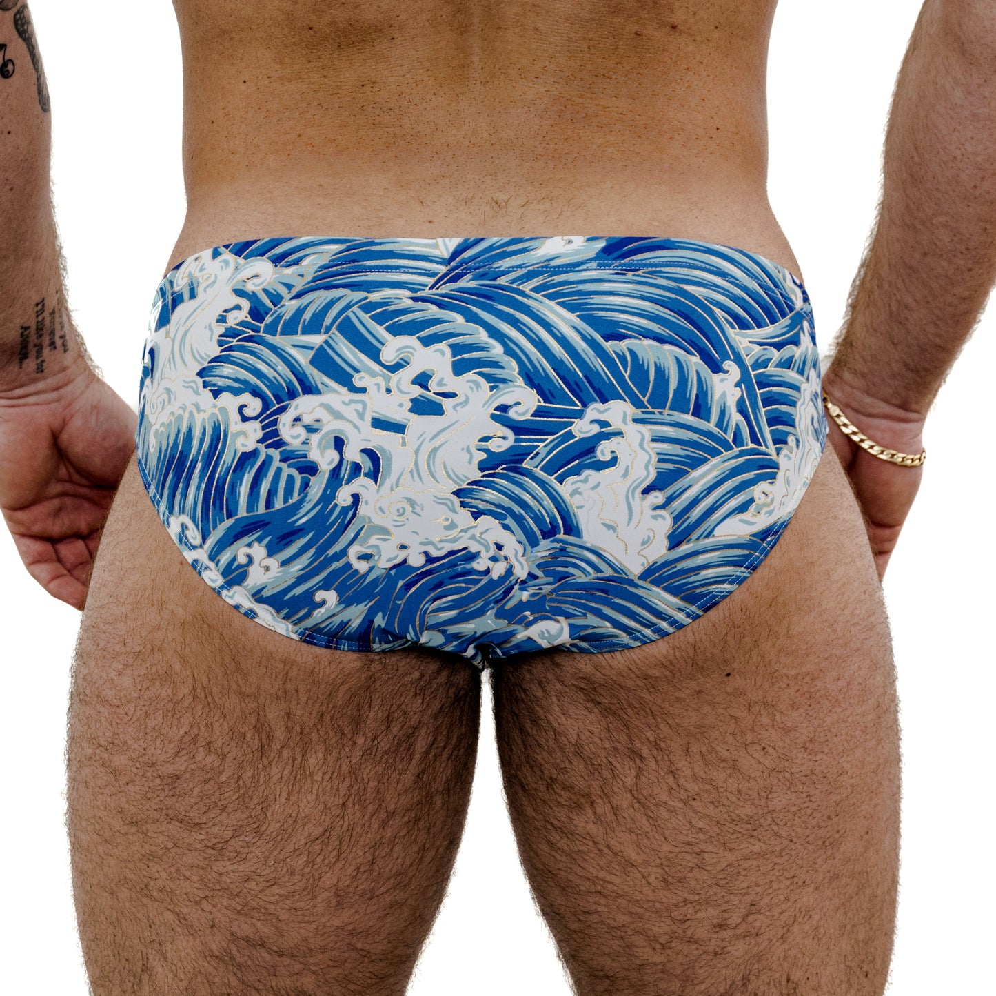 Blue and white wave-patterned speedo worn by a person on a white background