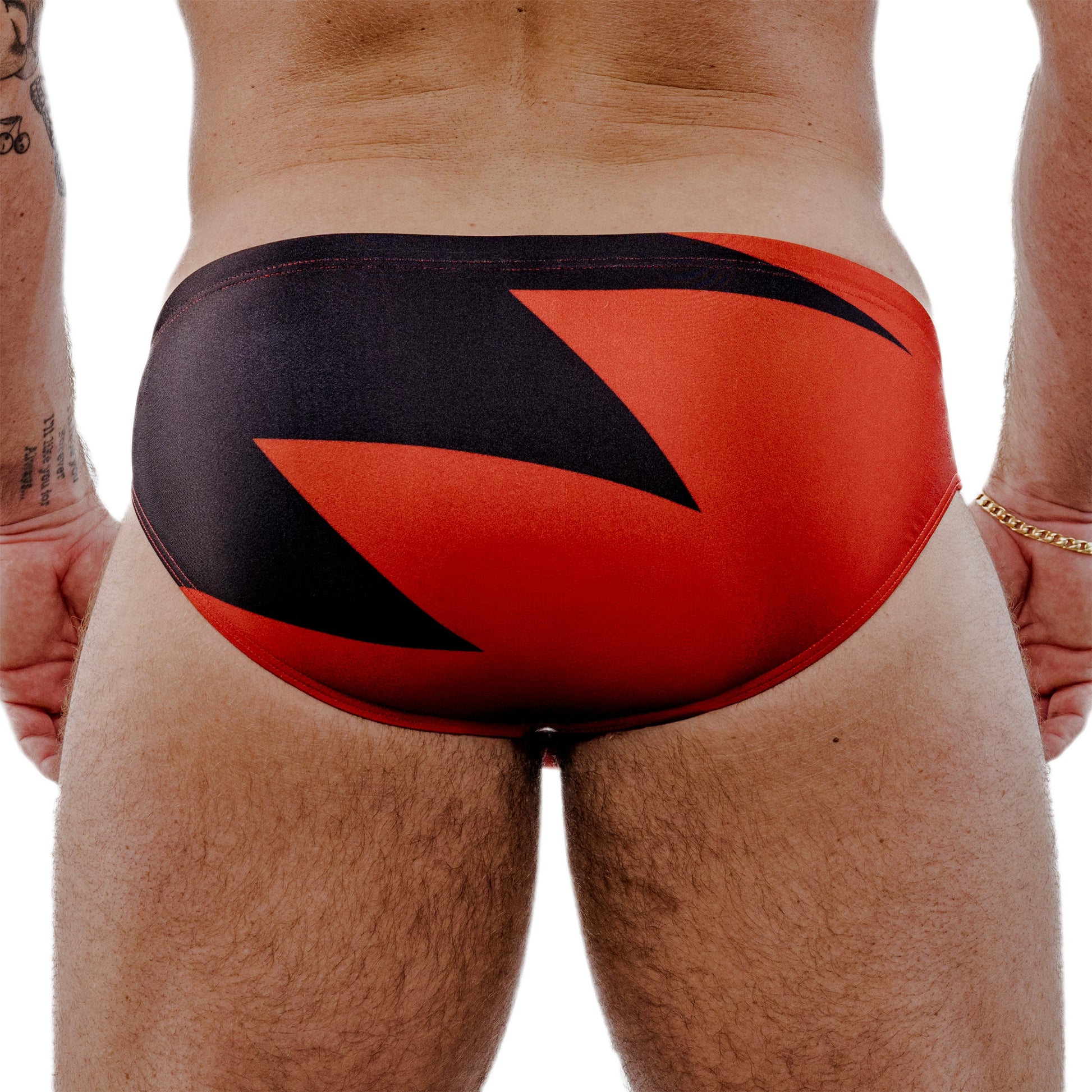 Red and black men's swimsuit on a person against a white background