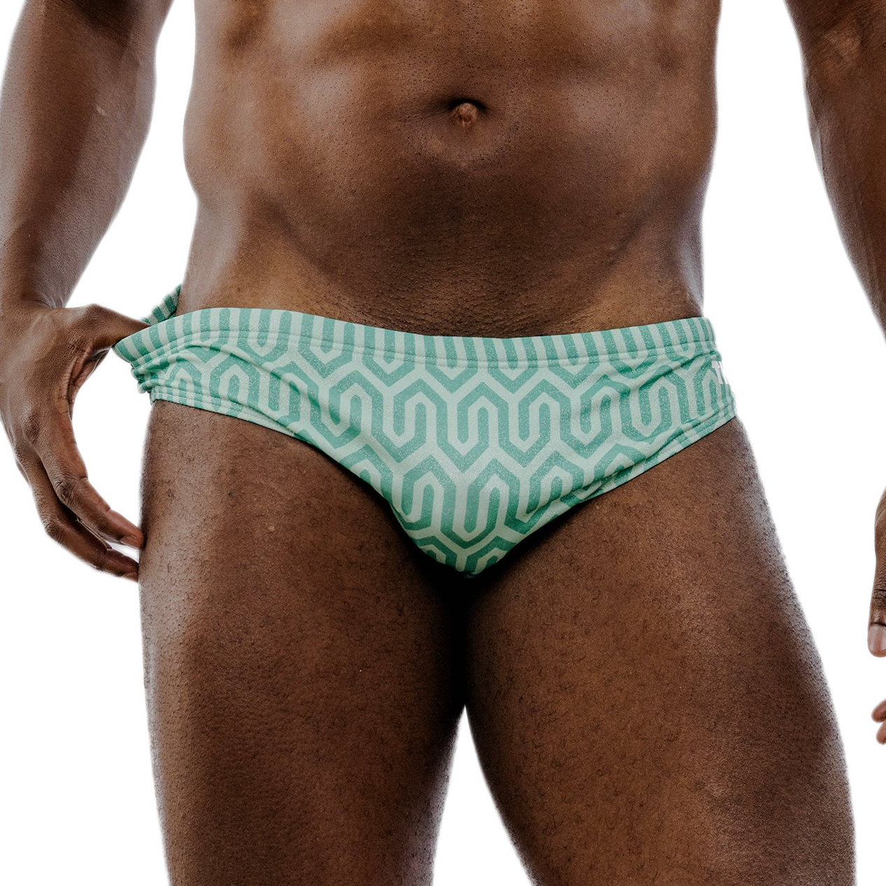 Green patterned swim briefs worn by a person on a white background