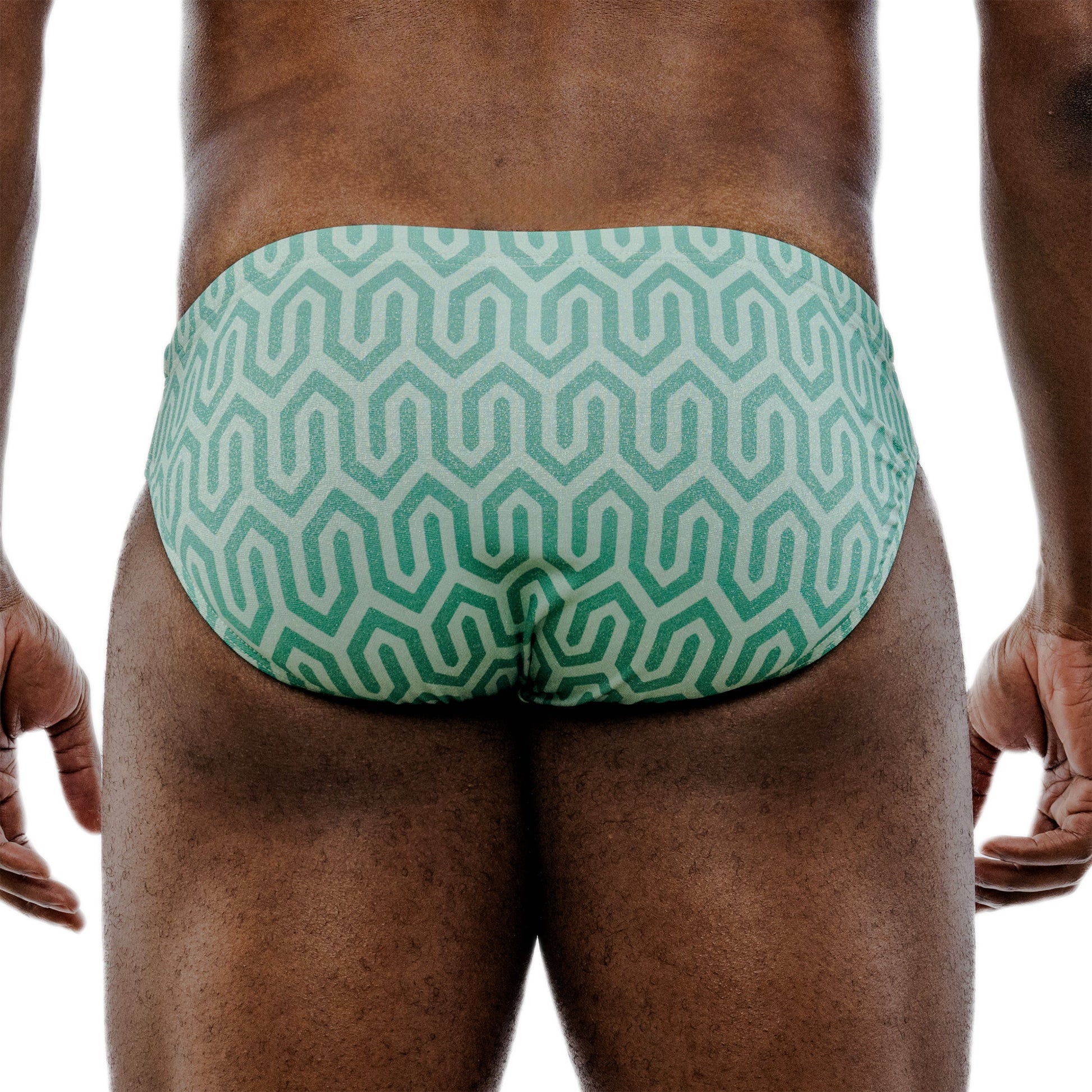 Green patterned swim briefs worn by a person on a white background