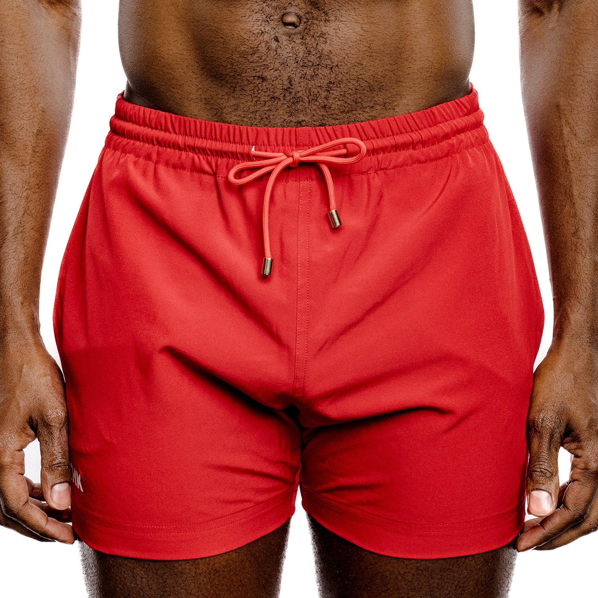 Red swim trunks worn by a person on a white background