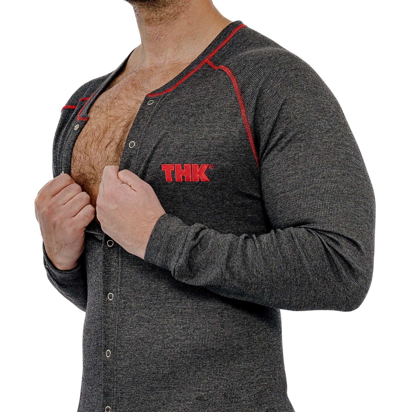 Man wearing a gray union suit with red accents and 'THK' logo, lifting shirt to reveal chest.