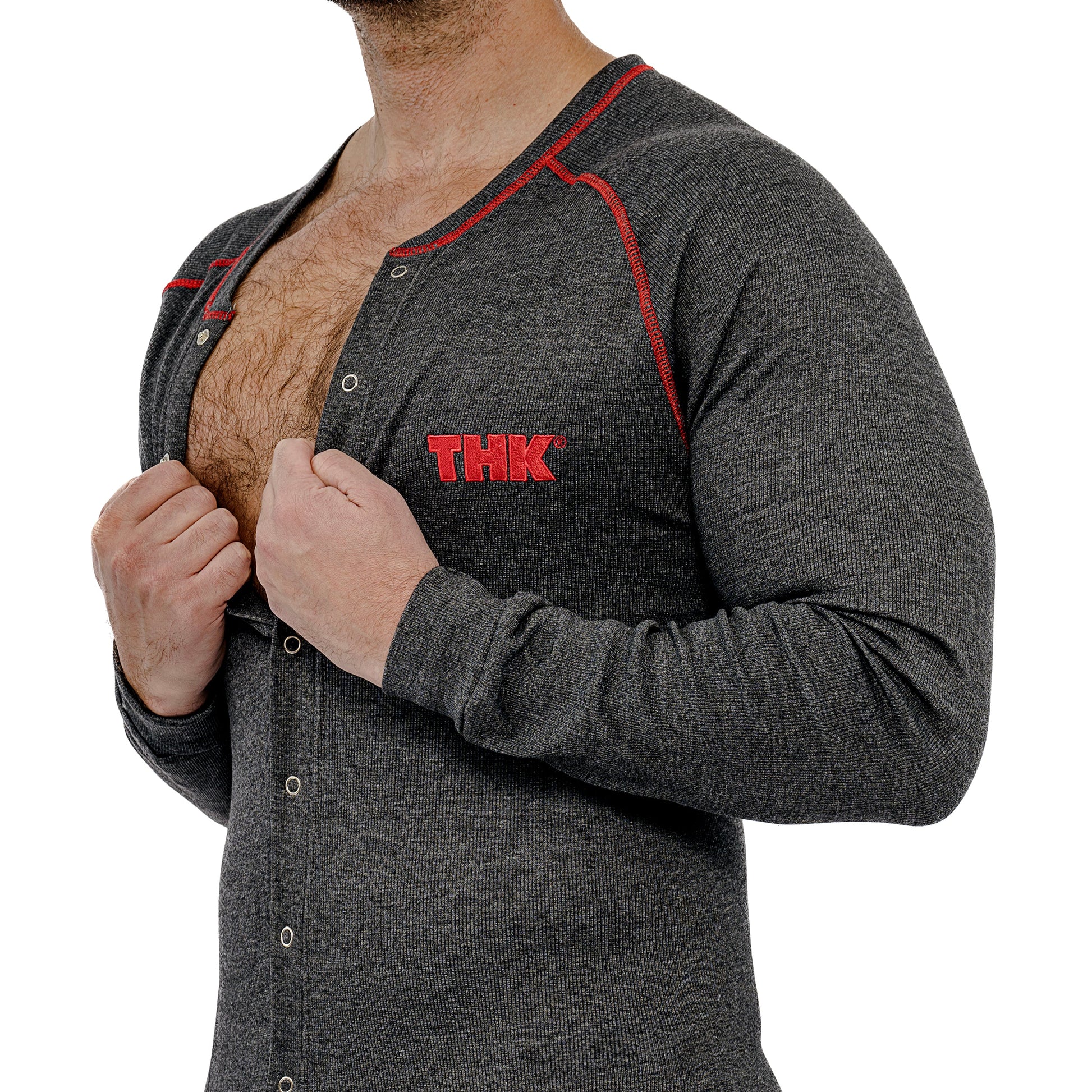 Man wearing a gray union suit with red accents and 'THK' logo, lifting shirt to reveal chest.