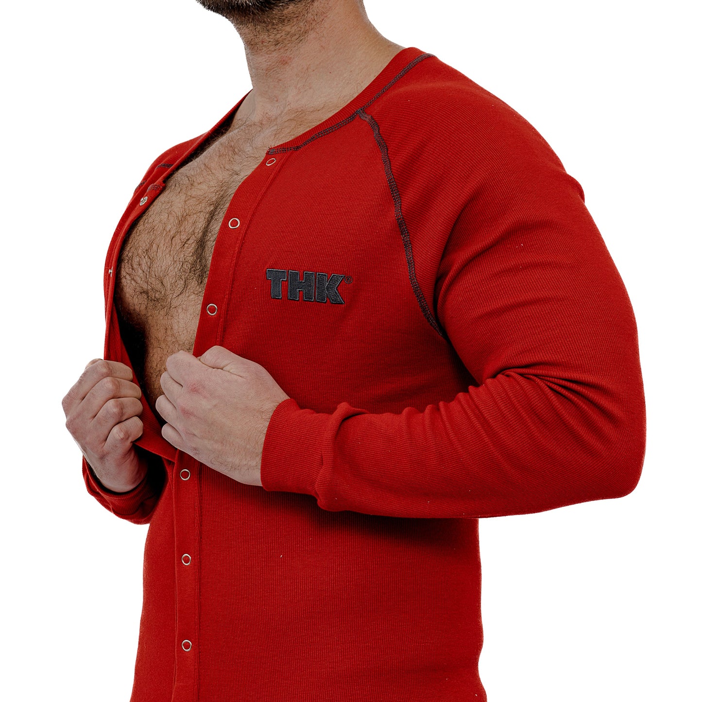 Red loungewear union suit with 'THK' logo being buttoned by a person on a white background