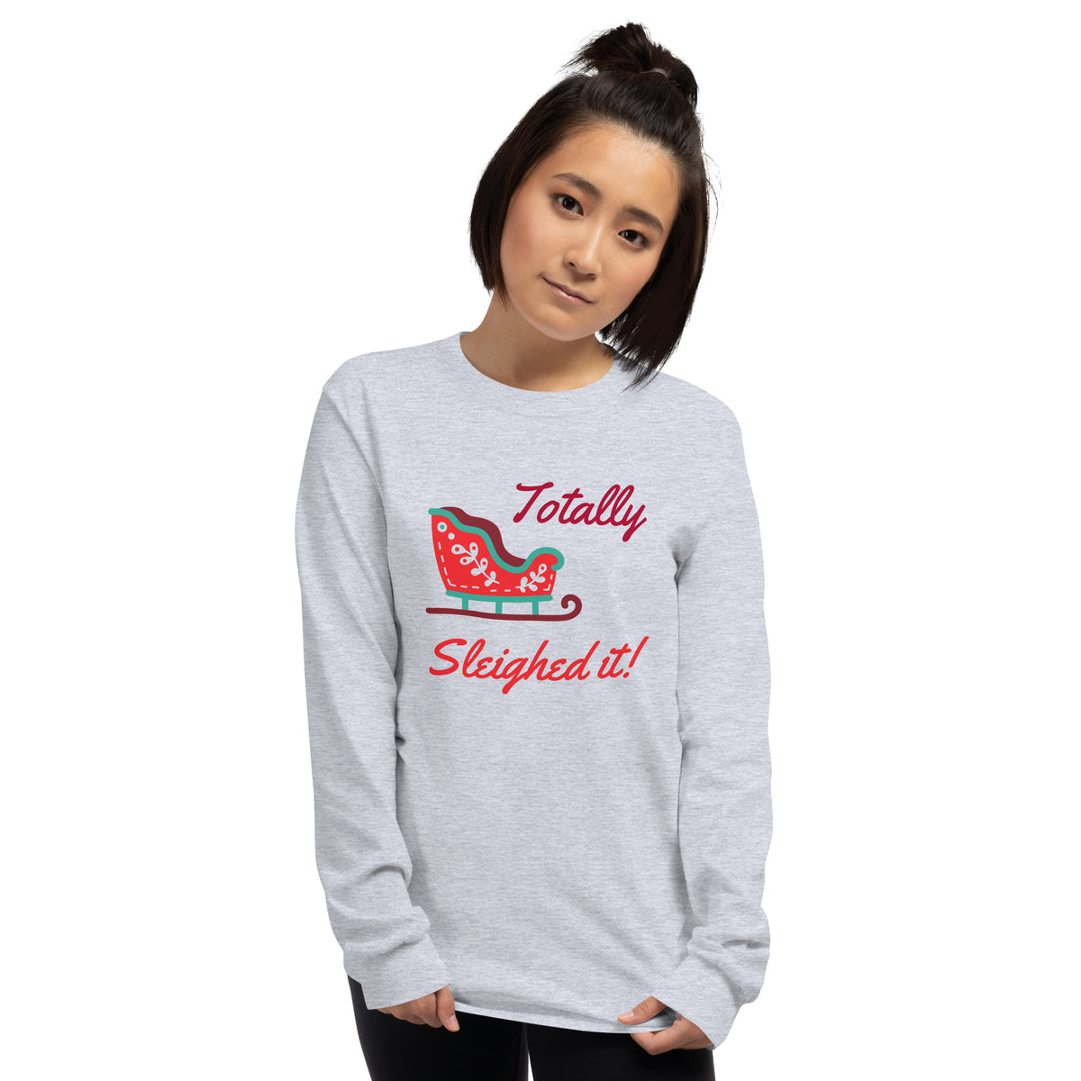person wearing a grey long sleeve tee shirt with a red holiday sleigh and red text that reads 'Totally Sleighed it!'