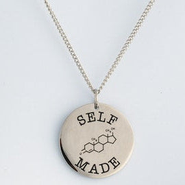 Necklace with a round pendant that reads 'SELF MADE' on a light gray background