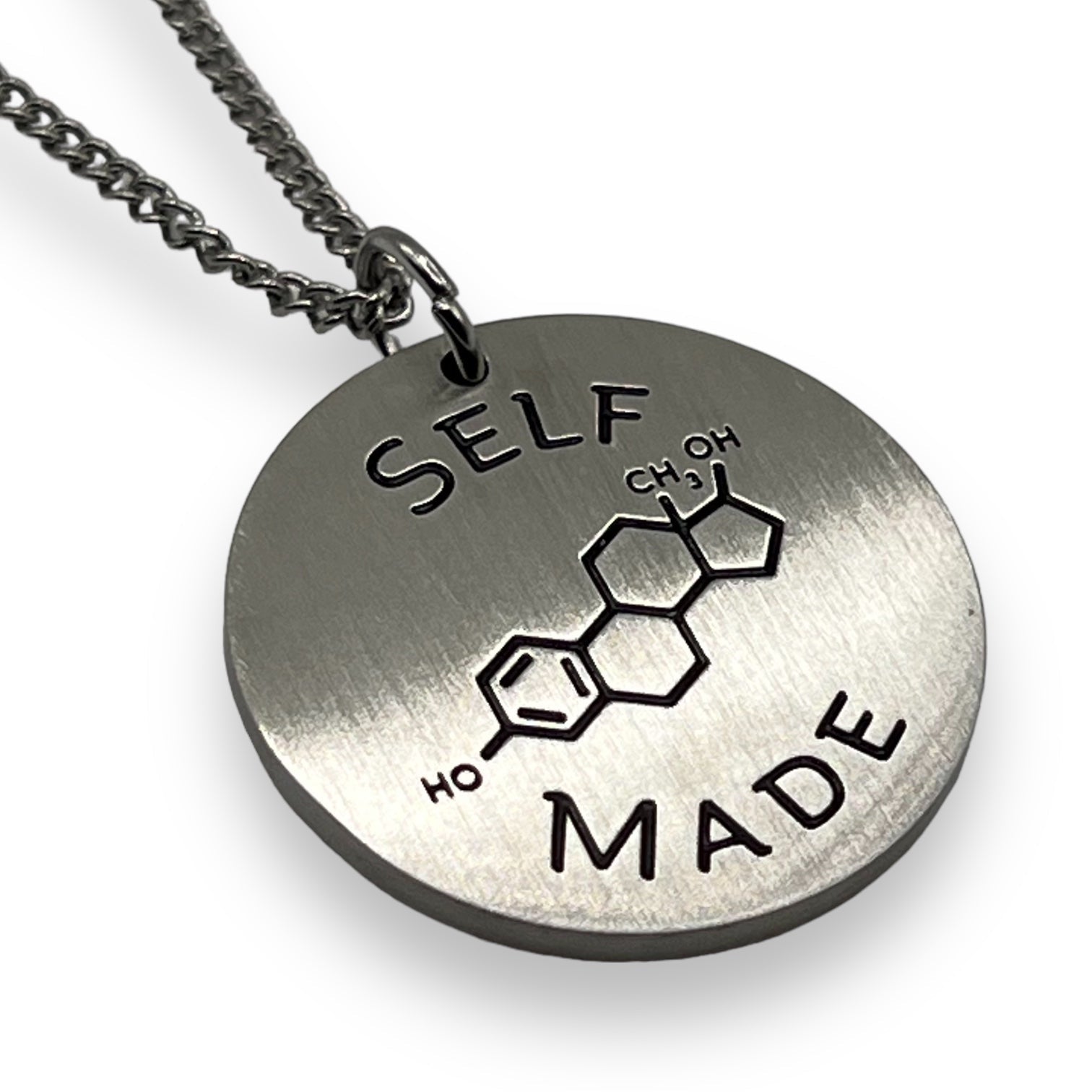 Silver necklace with pendant featuring chemical structure for estrogen and 'SELF MADE' transgender text on a white background