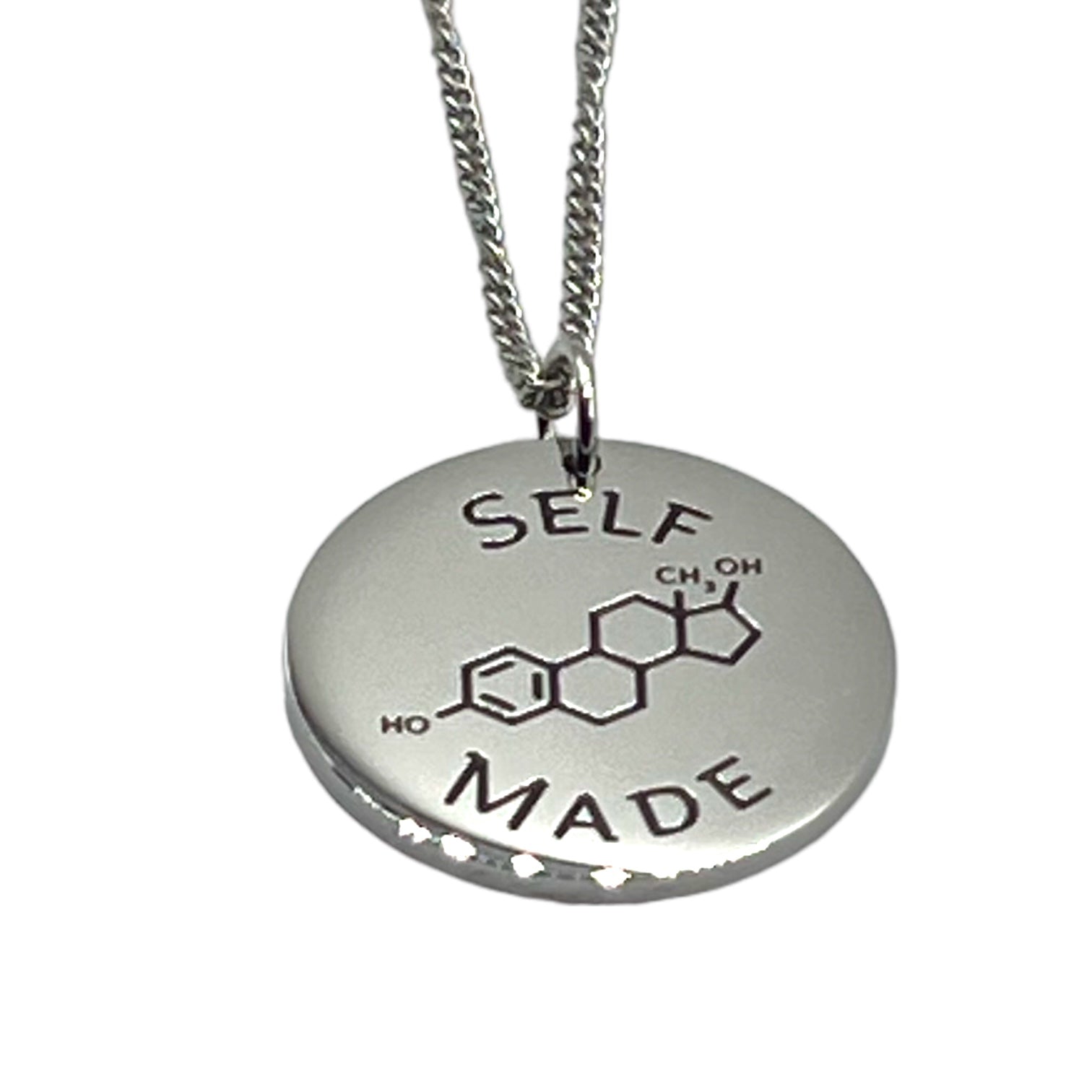 Silver necklace with a round pendant featuring estrogen chemical notation and 'SELF MADE' text on a white background.