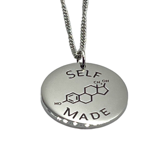 Silver necklace with a round pendant featuring estrogen chemical notation and 'SELF MADE' text on a white background.