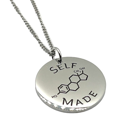 Silver necklace with a round pendant featuring chemical notation for estrogen and 'SELF MADE' text on a white background