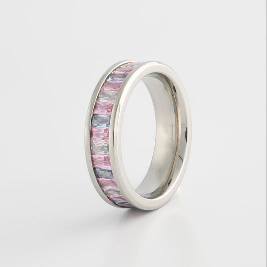 Silver ring with trans pride flag colored gems on a light gray background