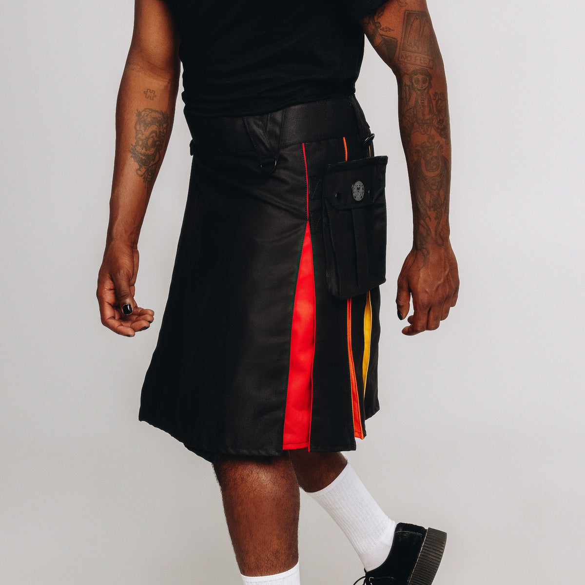 Person wearing a black leather kilt with rainbow accents on a white background