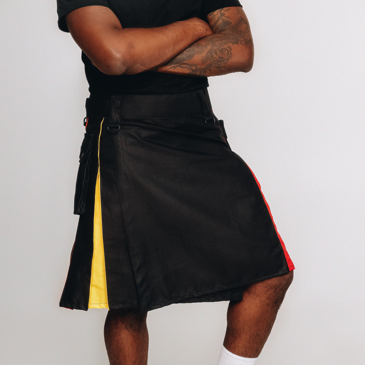 Person wearing a black kilt with rainbow lining on a white background