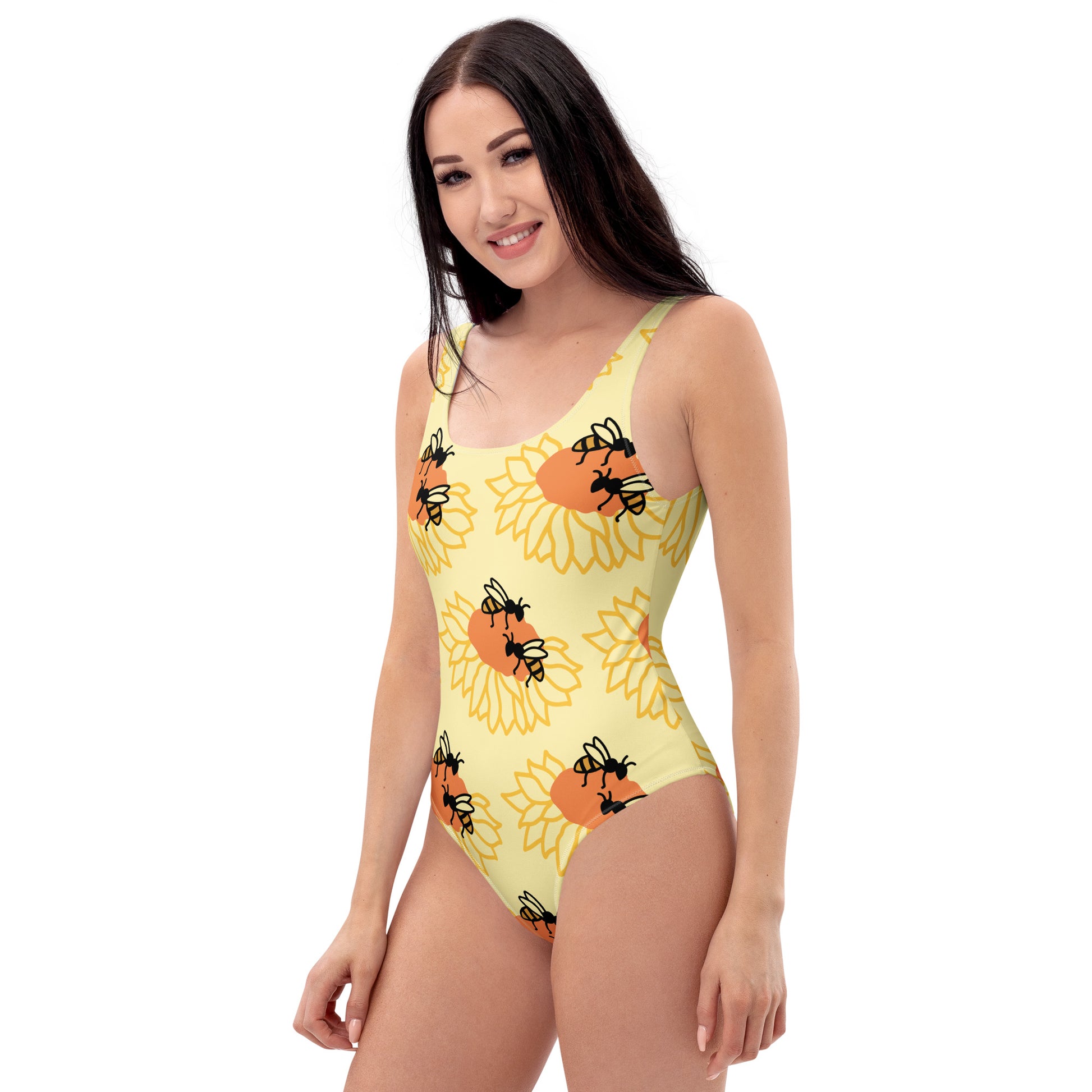 Woman wearing a yellow one-piece swimsuit with sunflower and bee pattern on a white background